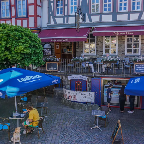 Der König-Adolf-Platz mit blauen Sonnenschirmen, Tischen und dem Café zum Löwen im Fachwerkhaus